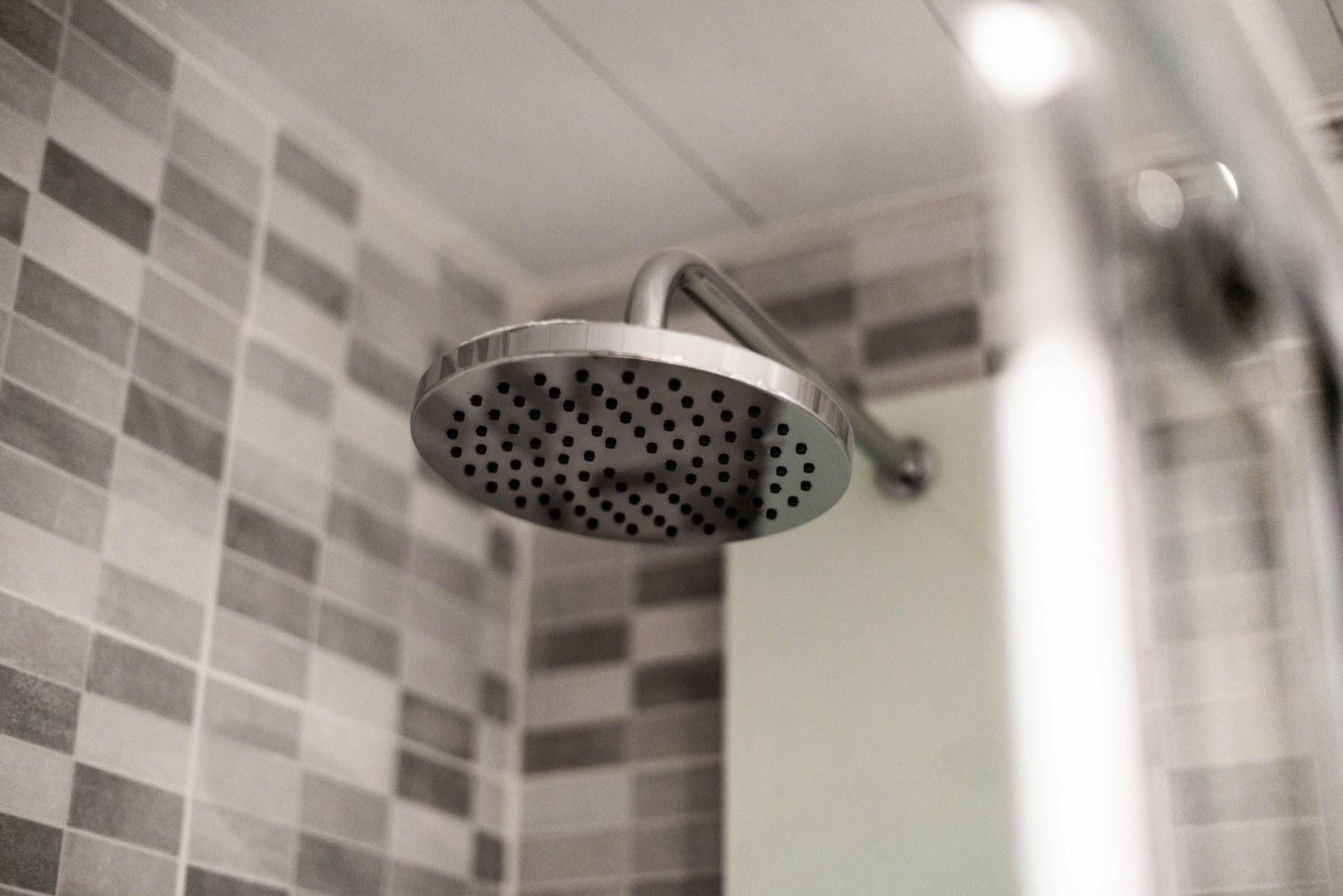 Round chrome rain shower head in a tiled shower