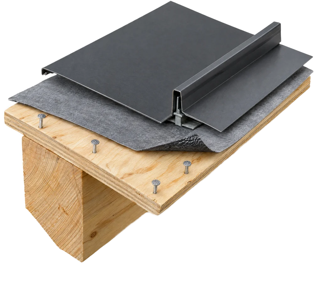 Cutaway of a roof assembly: rafter, plywood deck with ring-shank nails, peel-and-stick underlayment and a standing seam metal panel
